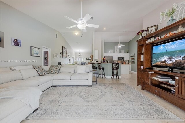 tiled living room with lofted ceiling and ceiling fan with notable chandelier