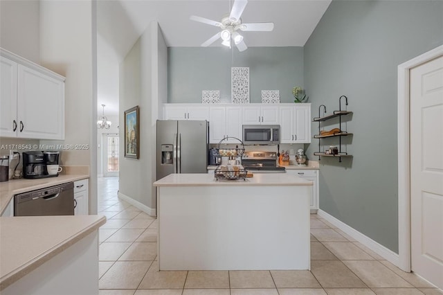 kitchen with a kitchen island, ceiling fan with notable chandelier, white cabinetry, light tile patterned floors, and stainless steel appliances