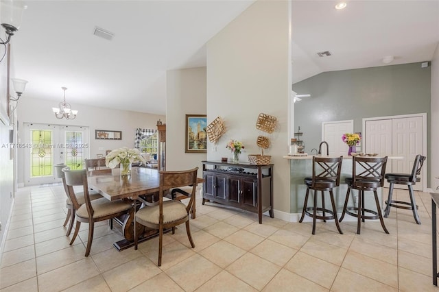 tiled dining room featuring french doors, a chandelier, and vaulted ceiling