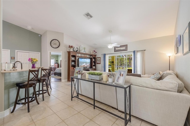 living room featuring vaulted ceiling, sink, light tile patterned floors, and ceiling fan