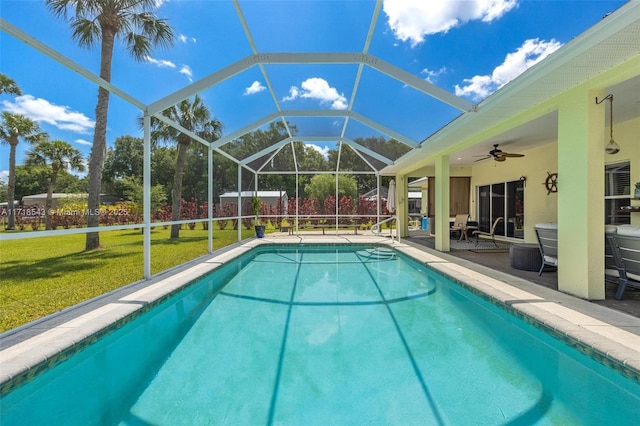 view of pool featuring ceiling fan, a patio area, glass enclosure, and a lawn