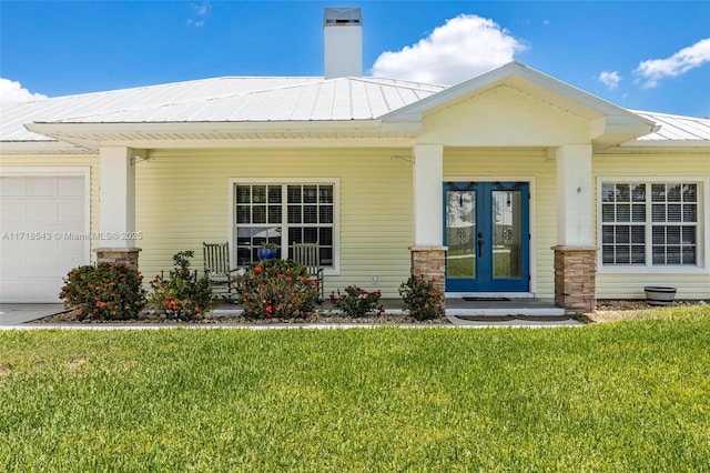 view of front of house with french doors, a garage, and a front yard