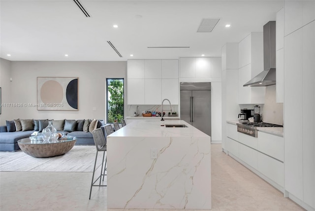 kitchen with sink, stainless steel appliances, white cabinetry, and wall chimney range hood