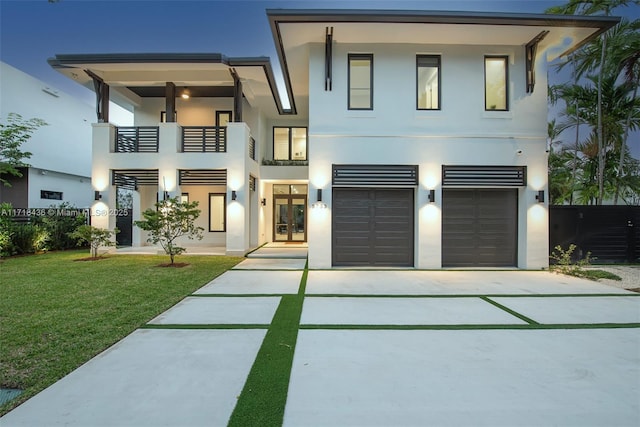 contemporary house featuring a front yard, french doors, a balcony, and a garage