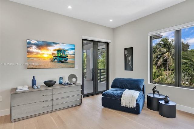 sitting room with plenty of natural light, light wood-type flooring, and french doors