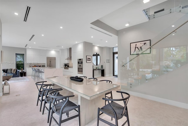 kitchen with a kitchen breakfast bar, white cabinetry, wall chimney exhaust hood, and a spacious island