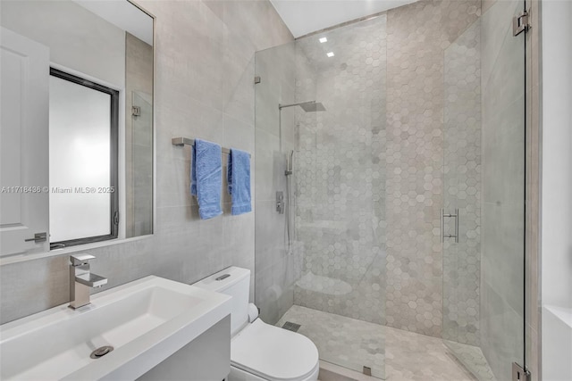 bathroom with an enclosed shower, vanity, toilet, and tile walls