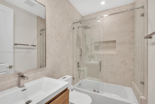 full bathroom with tasteful backsplash, toilet, shower / bath combination with glass door, vanity, and tile walls