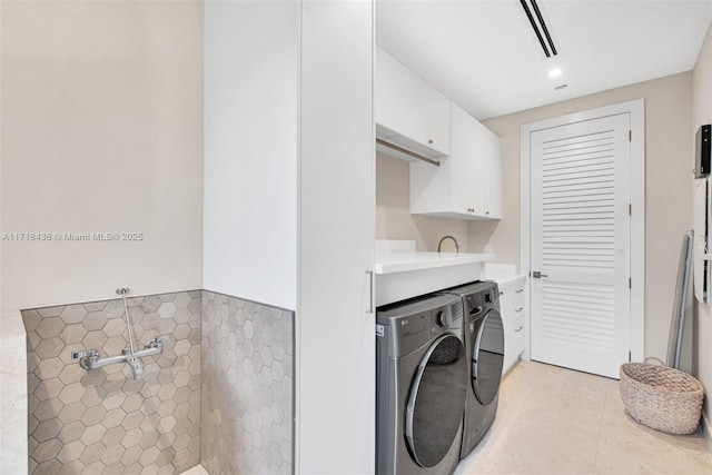 laundry area featuring washer and dryer, light tile patterned floors, cabinets, and tile walls