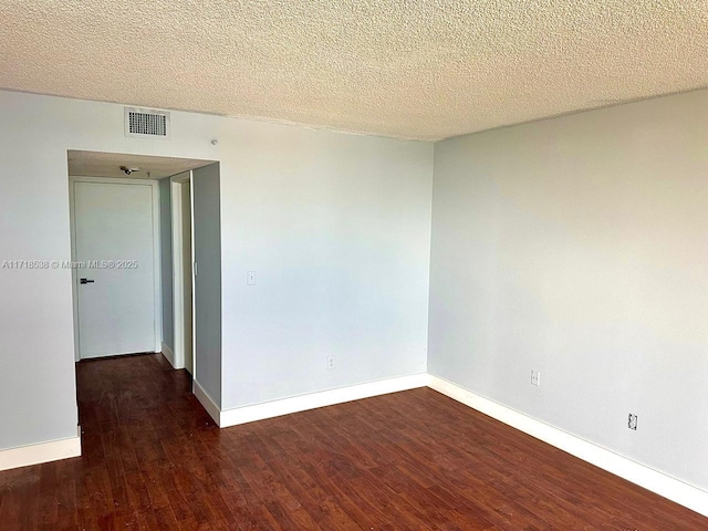 empty room with dark hardwood / wood-style floors and a textured ceiling