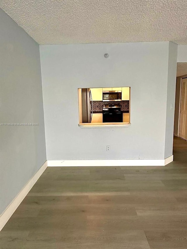 unfurnished room with hardwood / wood-style floors and a textured ceiling