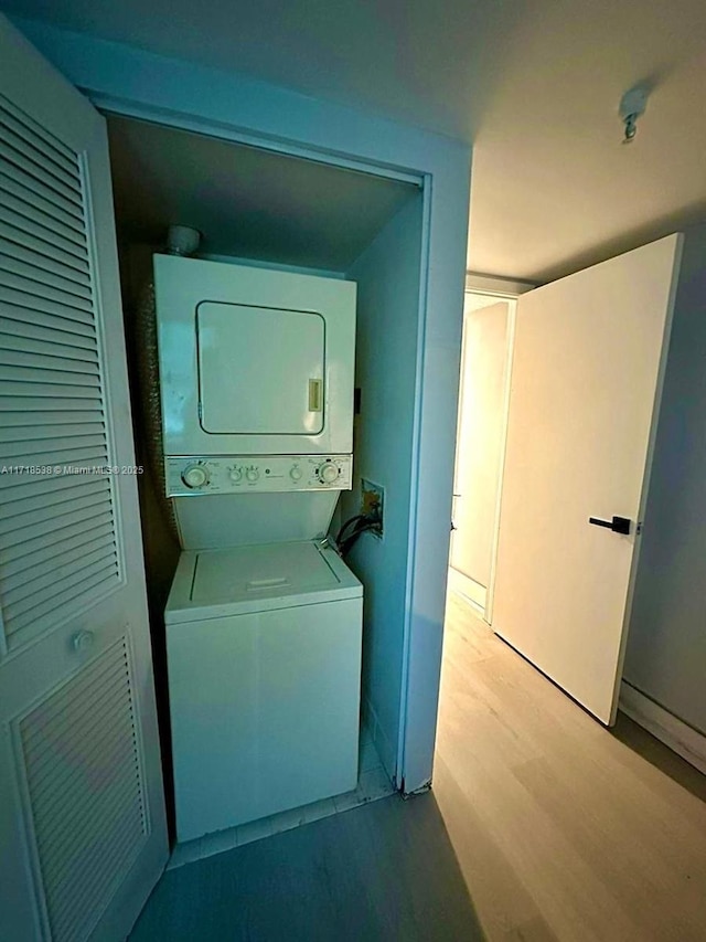 laundry area with light hardwood / wood-style flooring and stacked washer and clothes dryer