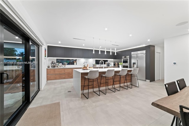 kitchen featuring a kitchen breakfast bar, a kitchen island with sink, sink, and appliances with stainless steel finishes