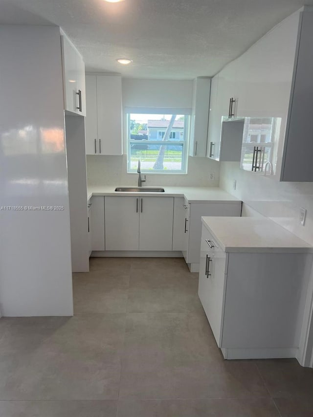 kitchen featuring decorative backsplash, white cabinetry, and sink