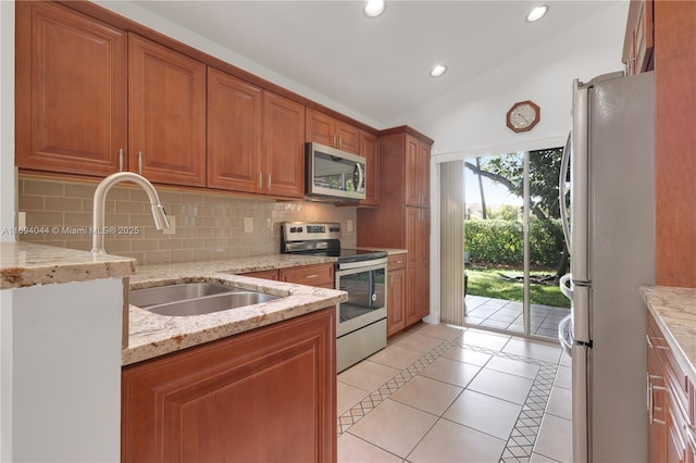 kitchen with light stone countertops, appliances with stainless steel finishes, tasteful backsplash, vaulted ceiling, and light tile patterned flooring