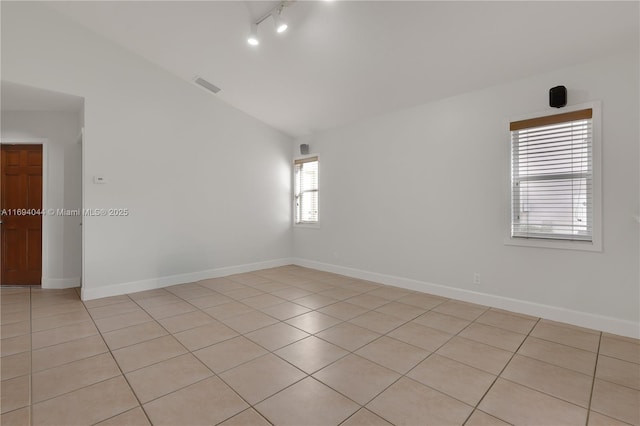 spare room featuring light tile patterned floors and vaulted ceiling