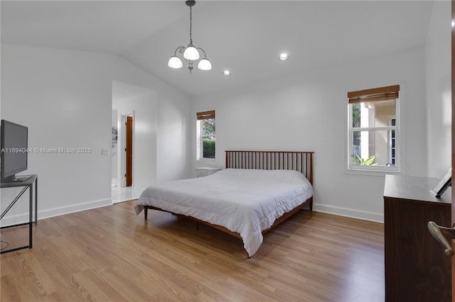 bedroom featuring an inviting chandelier, lofted ceiling, and light wood-type flooring