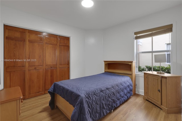 bedroom with light hardwood / wood-style floors and a closet