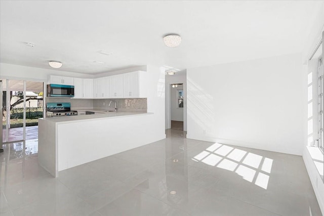 kitchen featuring white cabinetry, sink, kitchen peninsula, stove, and light tile patterned floors