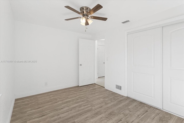 unfurnished bedroom featuring ceiling fan, light hardwood / wood-style floors, and a closet