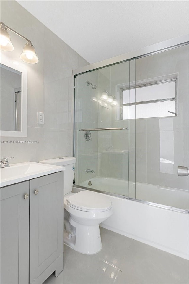 full bathroom with decorative backsplash, vanity, shower / bath combination with glass door, tile walls, and toilet