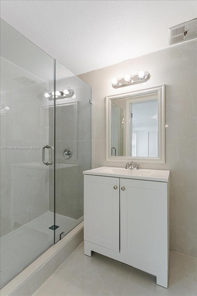 bathroom with tile patterned floors, a textured ceiling, vanity, and an enclosed shower