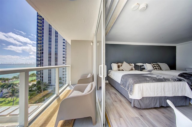 bedroom with hardwood / wood-style flooring, a wall of windows, and crown molding