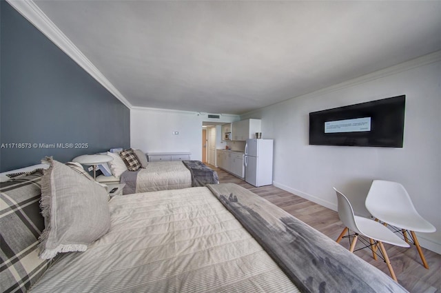 bedroom featuring white fridge, light hardwood / wood-style floors, and ornamental molding