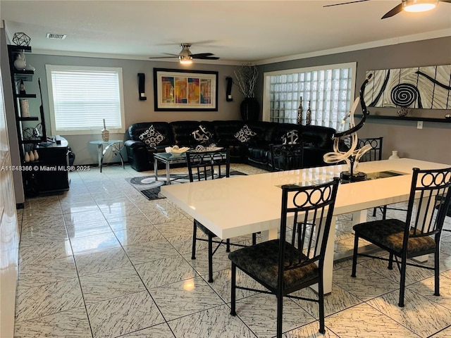 dining space featuring ceiling fan and crown molding