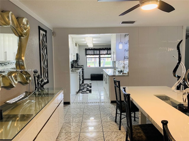 kitchen with white gas range, white cabinetry, and ceiling fan