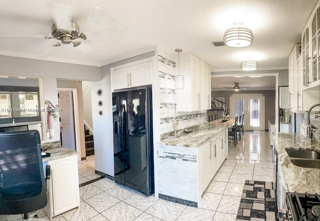 kitchen featuring white cabinets, black fridge with ice dispenser, light stone countertops, and hanging light fixtures