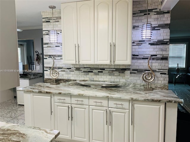 kitchen featuring tasteful backsplash, white cabinetry, light stone countertops, and ornamental molding