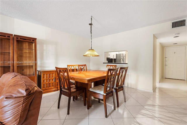 tiled dining area featuring a textured ceiling