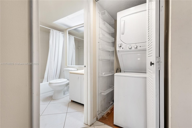 laundry area with stacked washer / dryer and light tile patterned flooring