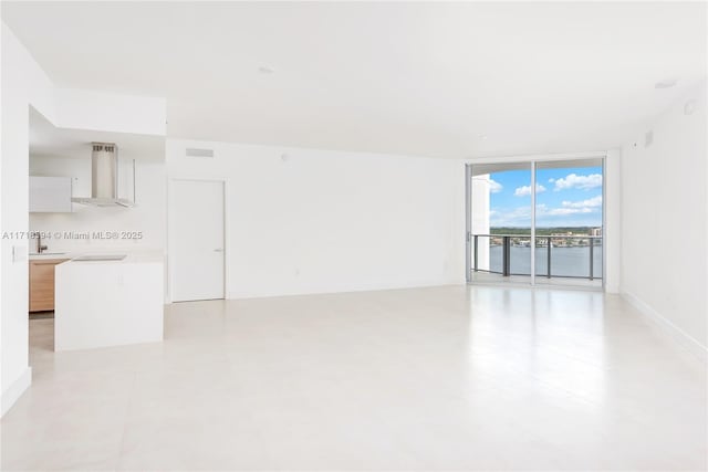 unfurnished room with a wall of windows and sink