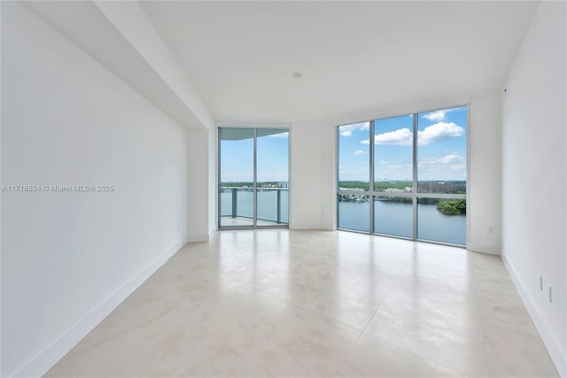 unfurnished room with a water view, floor to ceiling windows, and a healthy amount of sunlight