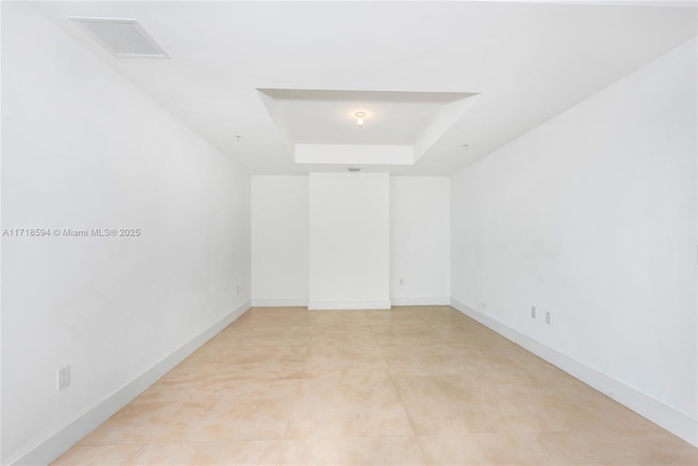 unfurnished room with a raised ceiling and light tile patterned floors