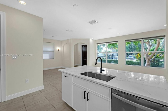 kitchen with light stone countertops, sink, dishwasher, white cabinetry, and light tile patterned flooring