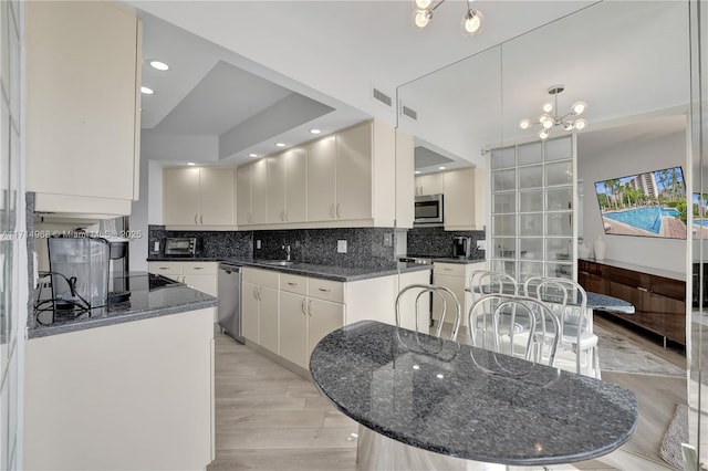 kitchen with a center island, sink, stainless steel appliances, dark stone counters, and decorative backsplash