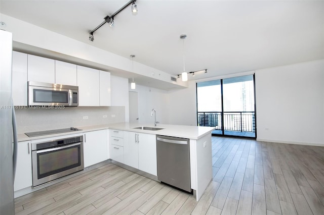 kitchen with white cabinetry, sink, hanging light fixtures, stainless steel appliances, and kitchen peninsula