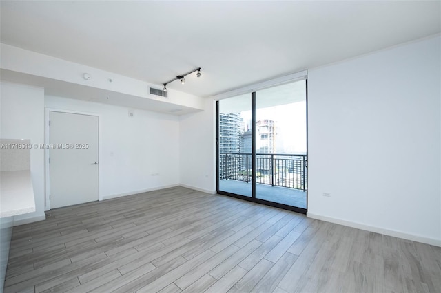 empty room featuring light wood-type flooring, track lighting, and floor to ceiling windows