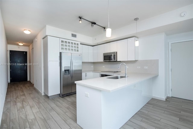 kitchen featuring pendant lighting, sink, decorative backsplash, appliances with stainless steel finishes, and white cabinetry