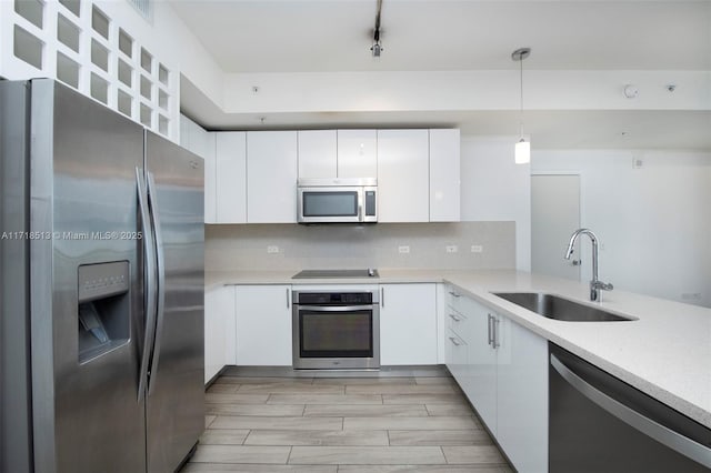 kitchen with pendant lighting, white cabinets, stainless steel appliances, and sink