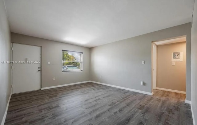 unfurnished room with dark hardwood / wood-style flooring