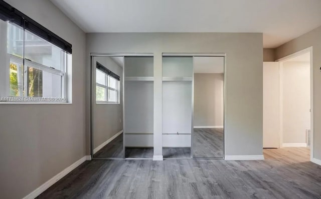 unfurnished bedroom featuring hardwood / wood-style floors and two closets