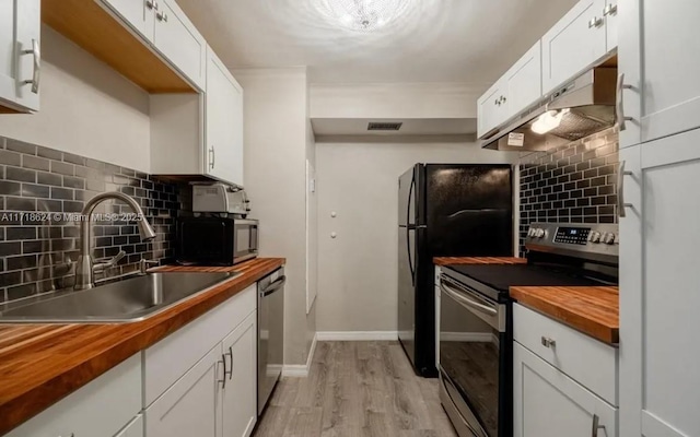 kitchen featuring tasteful backsplash, stainless steel appliances, sink, butcher block countertops, and white cabinetry