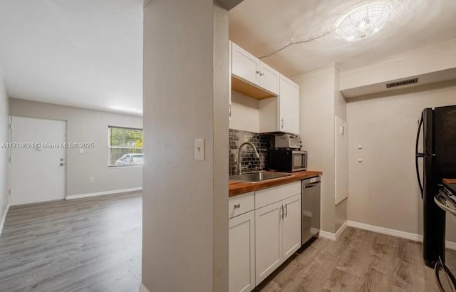 kitchen with butcher block countertops, white cabinetry, sink, and stainless steel appliances