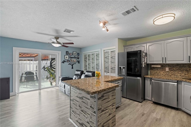 kitchen featuring ceiling fan, light hardwood / wood-style flooring, dark stone counters, gray cabinets, and appliances with stainless steel finishes