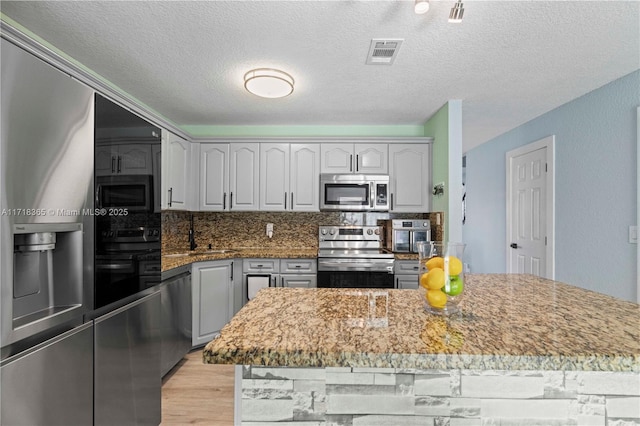 kitchen with gray cabinets, a center island, and appliances with stainless steel finishes