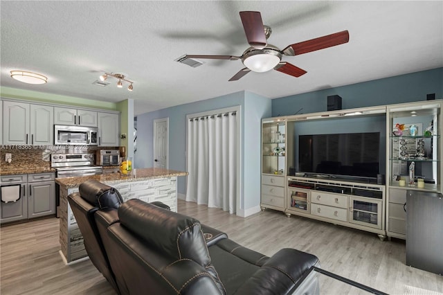 living room featuring a textured ceiling, light hardwood / wood-style floors, and ceiling fan